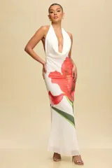 Vestido largo de fiesta color blanco con estampado de una flor roja. Tiene escote halter y espalda descubierta.