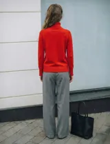 Polera de punto fino marca Nienty, color blanco, con cuello alto volcado y mangas largas con detalle de tajo en los puños.