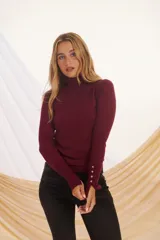 Polera color burdeos de manga larga, con cuello alto y botones en las mangas.