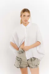 Camisa celeste de lino con corte amplio, cuello mao y mangas cortas. Presenta cierre frontal con botones y ribete negro en cuello y tapeta.