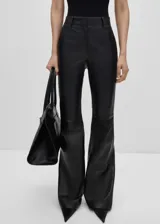 Pantalón de cuero ovino negro, de tiro alto y corte flare. Presenta trabillas, bolsillos laterales y traseros.