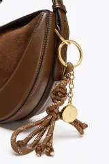 Charm para bolso con cuerda anudada color marrón y abalorios metálicos dorados.