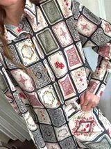 Camisa de lino con estampado de cartas de juego y dados, de corte clásico, con cuello camisero, cierre frontal con botones de madera y mangas largas.
