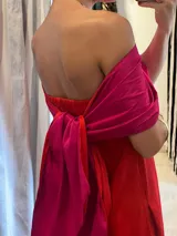 Vestido largo de tafeta, color rojo vibrante, con escote strapless y elástico en la espalda. Incluye una pieza de tela adicional color fucsia para usar como accesorio o parte superior.