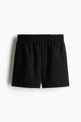 Short negro de corte holgado con tiro alto, cintura elástica fruncida y bolsillos laterales discretos.