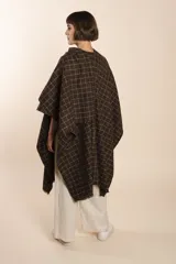 Ruana marrón con diseño a cuadros blancos, terminación envivada y flecos cortos.