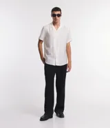 Camisa boxy de hombre confeccionada en viscolino color crudo con rayas texturizadas, cuello inglés, solapa, mangas cortas y abotonado frontal.