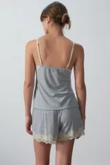 Conjunto de pijama gris compuesto por un top de breteles finos con puntilla en el escote y un short con puntilla en el ruedo.