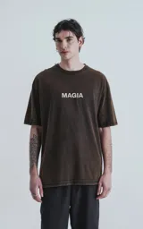 Remera negra con efecto gastado, de corte oversize y manga corta. Estampado en la espalda con dibujos de estilo esotérico en tonos violeta y naranja, y la palabra 'MAGIA' en blanco.