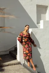 Vestido corto con estampado floral en tonos violeta, azul y amarillo. Tiene escote fruncido con cordones, mangas largas abullonadas y tajo lateral.