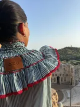 Blusa sin mangas a rayas verticales blancas y verdes, con cuello alto fruncido y volados decorativos en escote y hombros, con terminaciones en rojo.