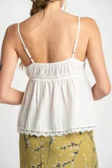 Blusa blanca de algodón con tirantes finos y escote en V. Presenta detalles de encaje en el escote y en el ruedo, y cierre frontal con botones.