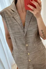 Vestido marrón con textura de lino, corte recto, sin mangas, cuello tipo blazer y cierre frontal con botones.