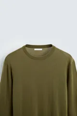Jersey negro de lana con acabado mercerizado, corte relaxed fit, cuello redondo y mangas largas con terminaciones en rib.