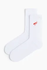 Par de medias blancas de caña alta acanalada con la palabra 'enjoy!' bordada en rojo.