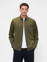 Camisa de manga larga color beige, de corte clásico, con cuello abotonado, bolsillo en el pecho y logo de oso bordado.