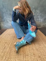 Bota tejana de caña corta en cuero metalizado celeste, con taco de 5 cm.