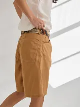 Bermuda color marrón claro, de tiro medio/alto, calce cómodo y relajado, con detalle de voladito en bolsillos.