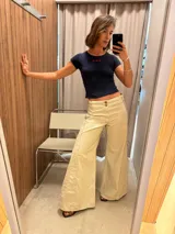 Pantalón jean de corte ancho color beige, con bolsillos delanteros y traseros.