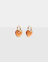 Aros dorados tipo argolla con dije de corazón de resina color naranja.