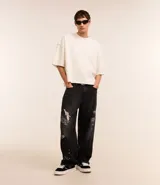 Pantalón masculino super baggy confeccionado en jeans sostenible con cintura con trabilla, cierre tradicional, bolsillos y estampa de grafiti.