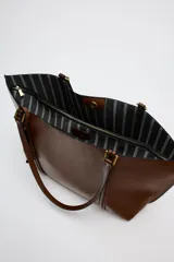Bolso negro tipo shopper con asa de hombro, detalle de colgador y bolsillo interior maxi. Cierre mediante imán.