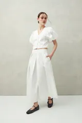 Falda midi blanca con pequeños lunares negros, de corte acampanado y cintura alta con pliegues.