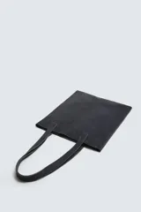 Bolso tipo shopper fabricado en piel con acabado serraje color gris oscuro. Tiene compartimento principal abierto con un bolsillo interior con cierre. Cuenta con dos asas de mano fabricadas en piel.