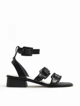 Sandalias negras de cuero con tacón bajo y tiras anchas con hebillas.