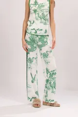 Pantalón de algodón blanco con estampado de palmeras, camellos y aves en color verde.