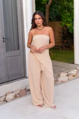 Conjunto de dos piezas color beige claro, compuesto por un top strapless con bajo asimétrico y un pantalón ancho de tiro alto.