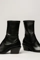 Bota de caña media color negro, de cuero sintético, con puntera cuadrada y taco geométrico.