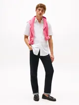 Camisa blanca a rayas verticales celestes, de corte clásico, manga corta, cuello abotonado y bolsillo en el pecho. Logo de Tommy Hilfiger bordado en el bolsillo.