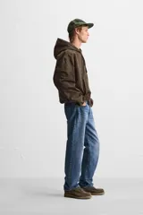 Cazadora relaxed fit confeccionada en tejido de algodón denim color marrón. Cuello con capucha ajustable y manga larga. Bolsillos frontales tipo canguro. Acabados con elástico. Efecto lavado. Cierre frontal de cremallera.