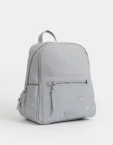 Mochila de cuerina color crema con estampado de flores bordadas, bolsillo frontal con cierre, correas regulables, manija superior, acceso con cierre superior, bolsillos laterales y tag de cuerina.