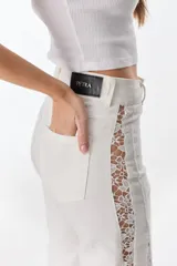 Pantalón de jean blanco de pierna ancha con cortes laterales de encaje que van desde la pretina al bajo del pantalón.