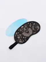 Antifaz para dormir de color negro con estampado esotérico en tonos rosados/cobre, que incluye motivos de sol, luna y estrellas. Incluye una bolsa de gel reutilizable de color azul claro.