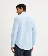 Camisa celeste de lino con cuello camisero, abotonadura frontal y mangas largas.