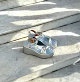 Sandalias doradas con plataforma, tiras cruzadas y hebilla al tobillo.