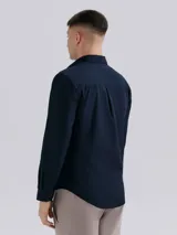 Camisa de vestir azul marino, de corte clásico, con cuello abotonado, manga larga y bolsillo en el pecho.