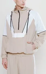 Anorak unisex beige y blanco con capucha, cierre parcial con cremallera, bolsillo tipo canguro con solapa y cordones ajustables con texto en la capucha.