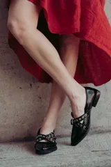 Chatitas de cuero negro con puntera redondeada y detalle de hebillas con ojales metálicos.