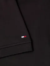 Chomba negra de Tommy Hilfiger, corte regular, con cuello gris a rayas y logo bordado en el pecho.