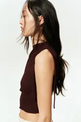 Top marrón sin mangas, de punto texturizado, con escote bote y cordones ajustables en un lateral y en un hombro.