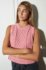 Chaleco tejido de algodón color rosa, con cuello redondo y diseño de punto trenzado.