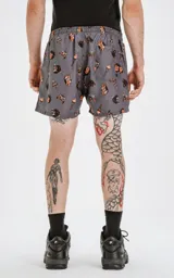 Short de baño gris con estampado de calaveras, dagas y llamas en tonos naranja y negro.