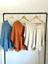 Remerón tipo poncho color naranja confeccionado en lino italiano, con escote en V y bolsillos laterales.