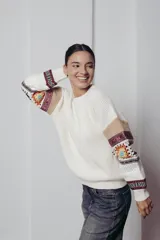 Sweater de punto color crema con cuello redondo y mangas largas con diseño geométrico en tonos beige, rojo, azul y blanco.