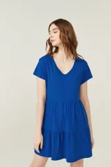 Vestido corto lila con cuello en V y mangas cortas. Tiene corte holgado y dos volados en la falda.