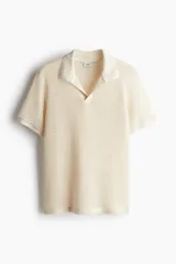 Remera polo de manga corta color crema, con tejido de malla tipo crochet, cuello clásico y abertura en V.
